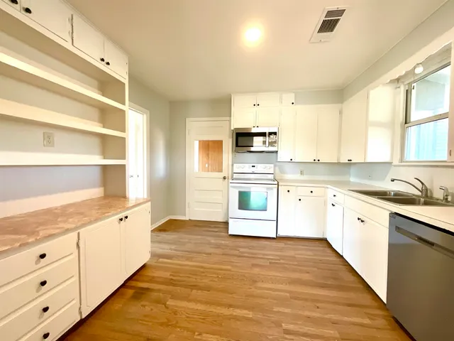 a large kitchen with stainless steel appliances cabinets a sink and a window
