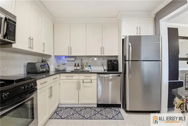 a kitchen with stainless steel appliances granite countertop a refrigerator a stove a sink and white cabinets