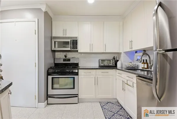 a kitchen with stainless steel appliances granite countertop a stove a refrigerator and a microwave