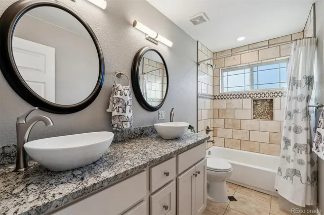 a bathroom with a granite countertop toilet a sink and a mirror