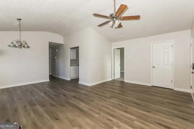 a view of empty room with wooden floor and ceiling fan