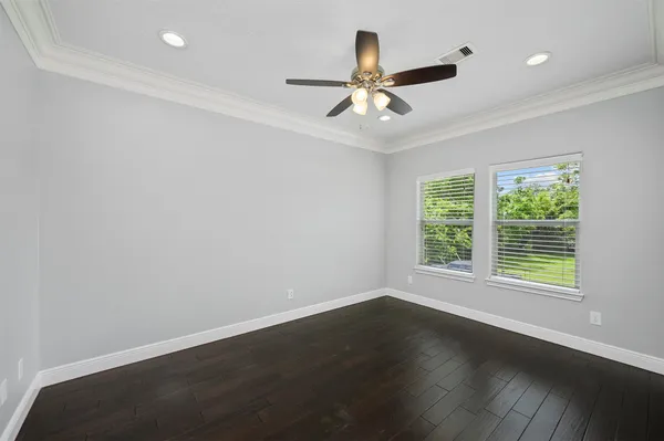 an empty room with wooden floor fan and windows