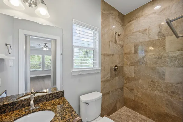 a bathroom with a granite countertop sink toilet and shower