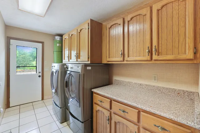 an empty room with a chandelier fan and windows