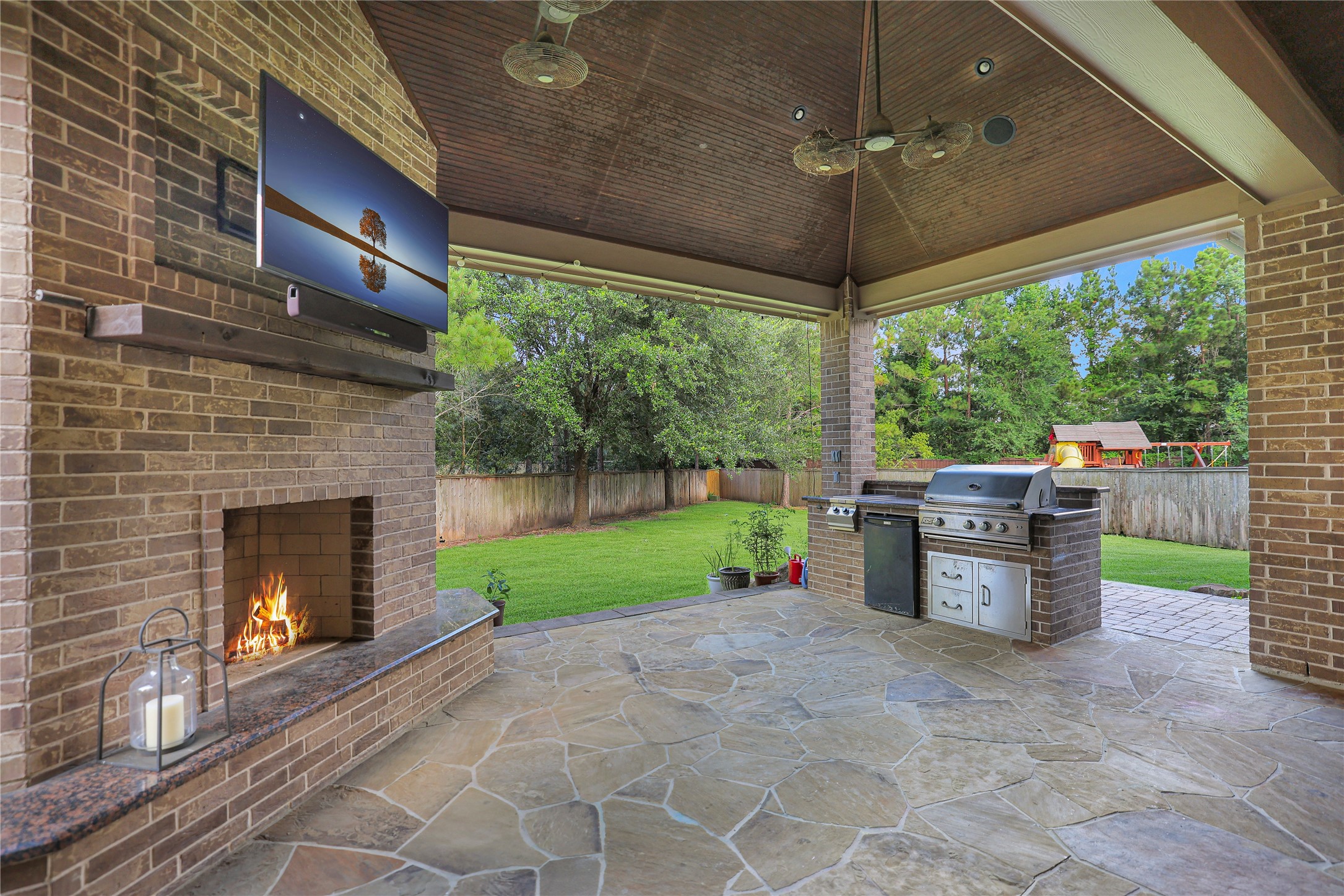 3 Mohawk Path Place Spring, TX 77389 - Photo 28 of 38 The large covered patio is the perfect gathering space for enjoying the outdoors year-round. Stay cool on warm summer days with the ceiling fans, or cozy up by the fireplace on chilly winter evenings. Complete with a built-in grilling station, this outdoor living area is ideal for entertaining while overlooking the spacious backyard.