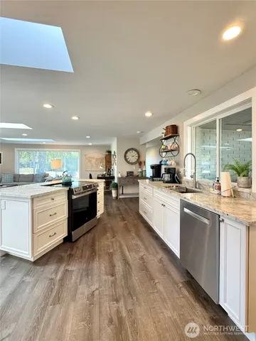 a kitchen with granite countertop white cabinets and white stainless steel appliances