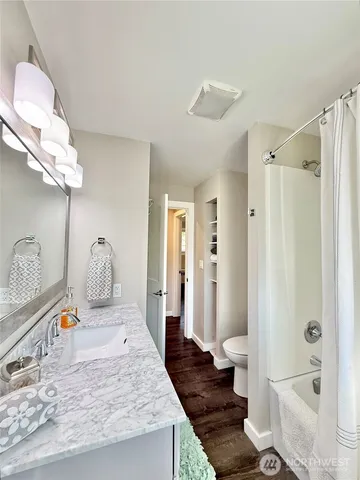 a bathroom with a granite countertop sink a toilet and shower