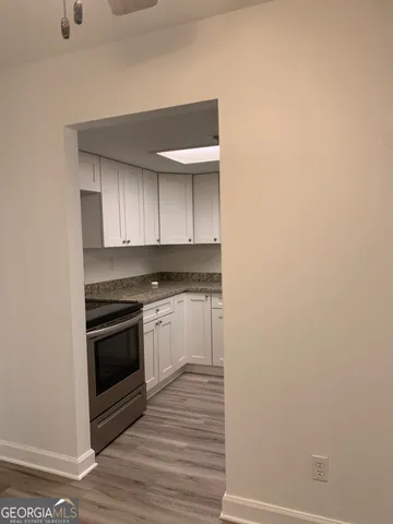 a kitchen with granite countertop white cabinets and stainless steel appliances