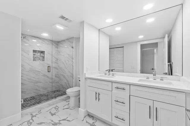 a bathroom with a sink a toilet a mirror and shower