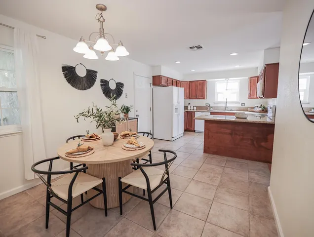 a dining room filled chandelier and kitchen view