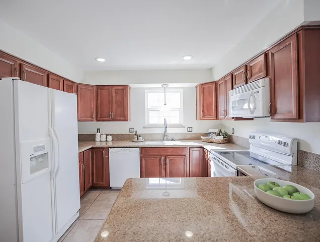 a large kitchen with stainless steel appliances granite countertop a refrigerator sink and cabinets