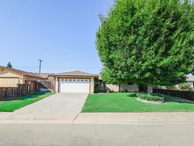 a view of a house with a yard and large trees