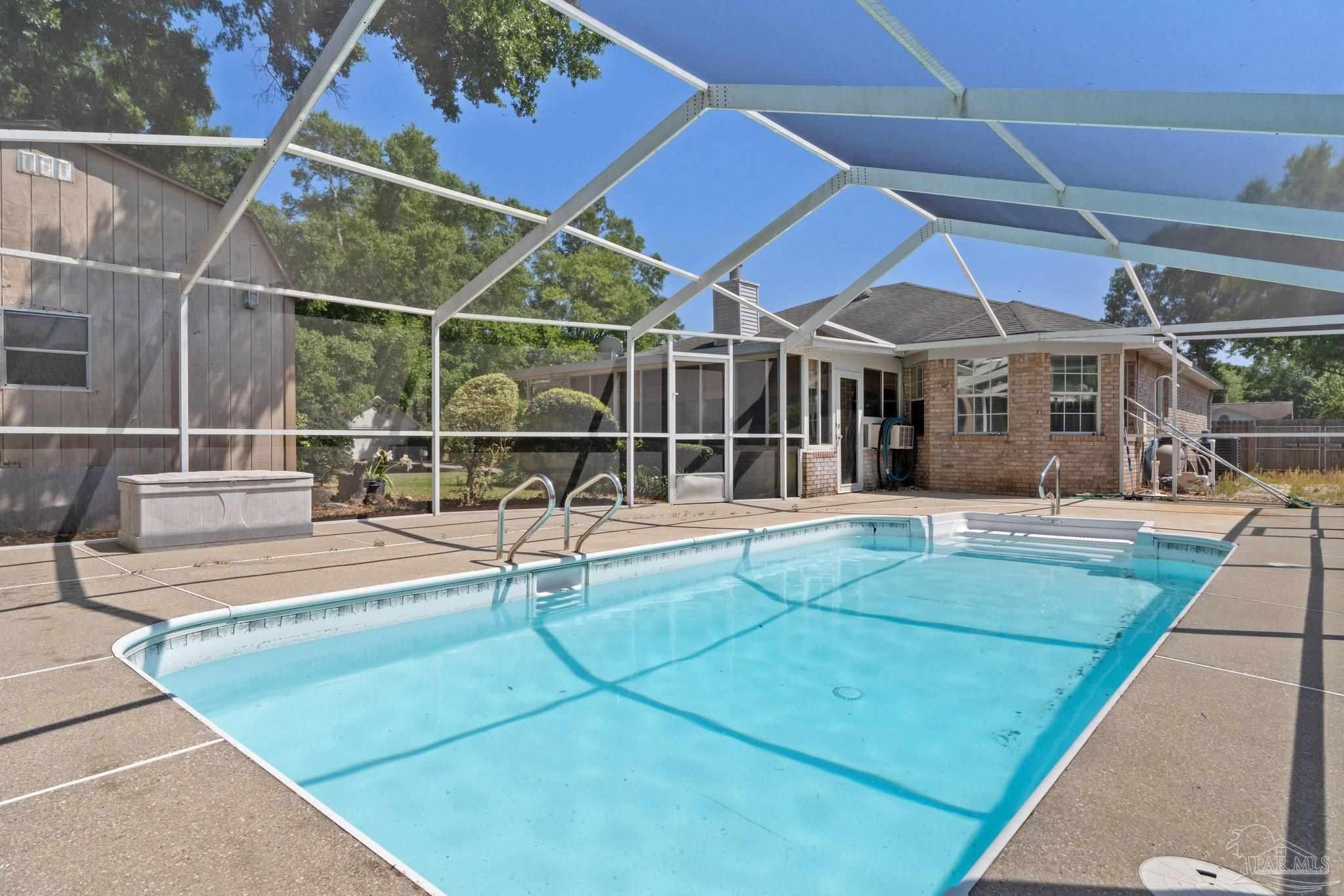 a view of a backyard with a swimming pool and furniture