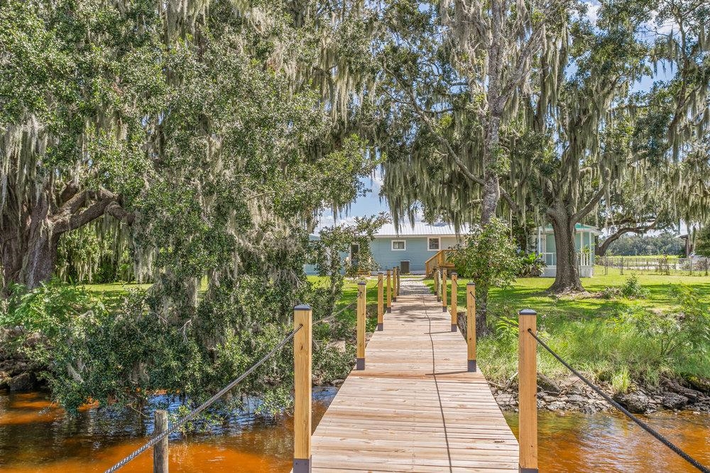 137 Mays Cove Road East Palatka, FL 32131 - Photo 46 of 70 a view of a patio with table and chairs and couches with wooden fence and trees