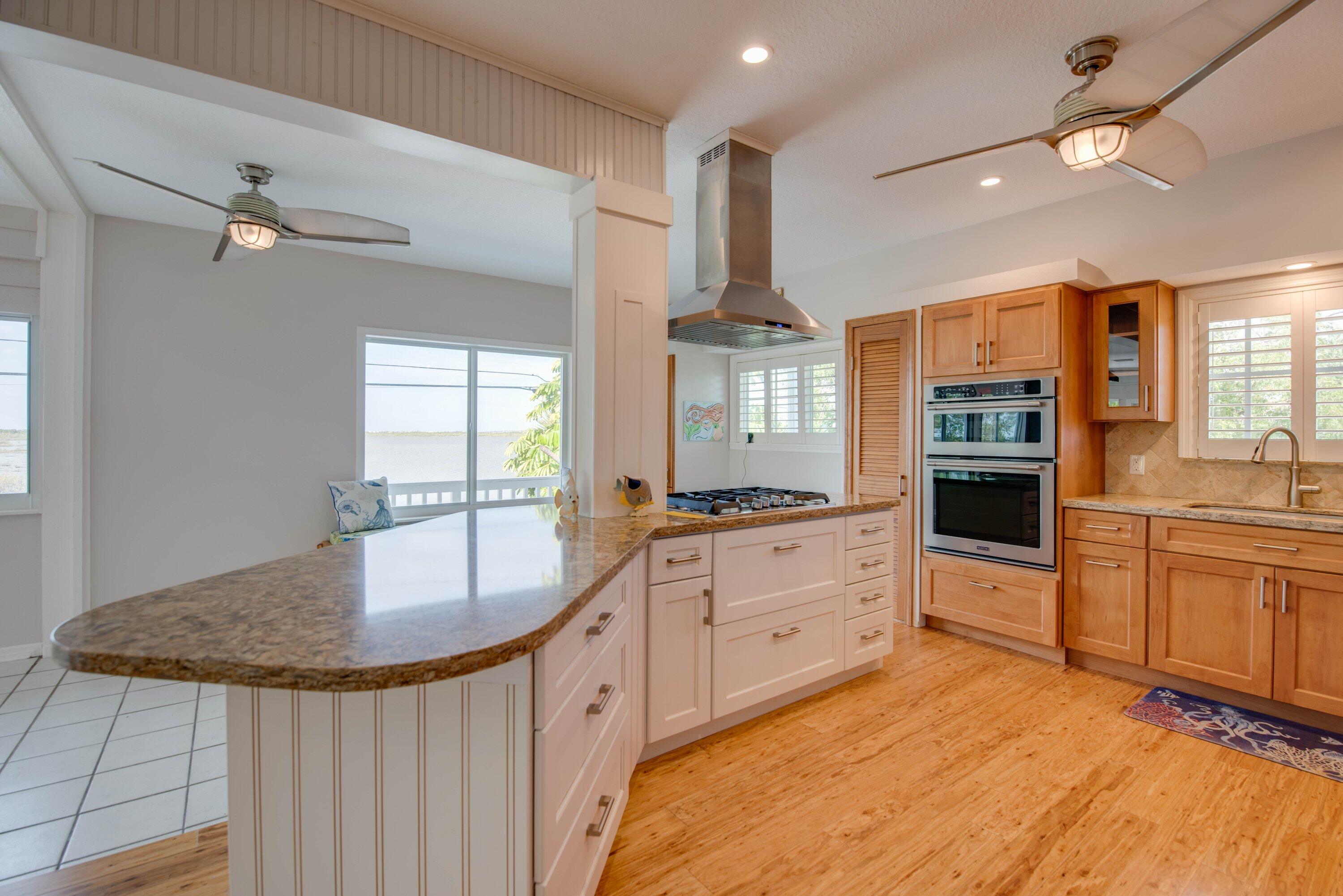 643 Indies Road Summerland Key, FL 33042 - Photo 44 of 50 a large kitchen with kitchen island granite countertop a stove a sink a window and dining table
