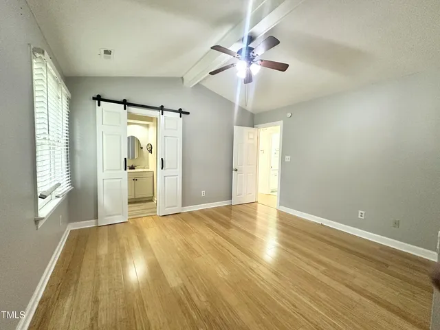 a view of an empty room with a window and wooden floor