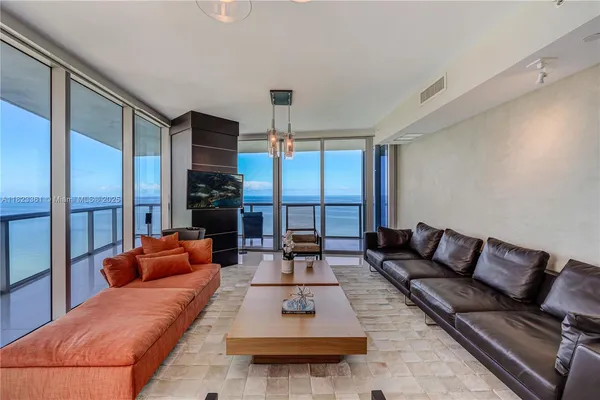 a living room with furniture fireplace and large windows