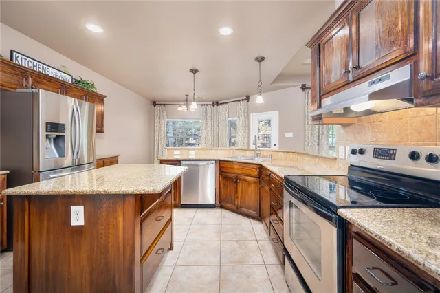a large kitchen with granite countertop a large counter top space appliances and cabinets