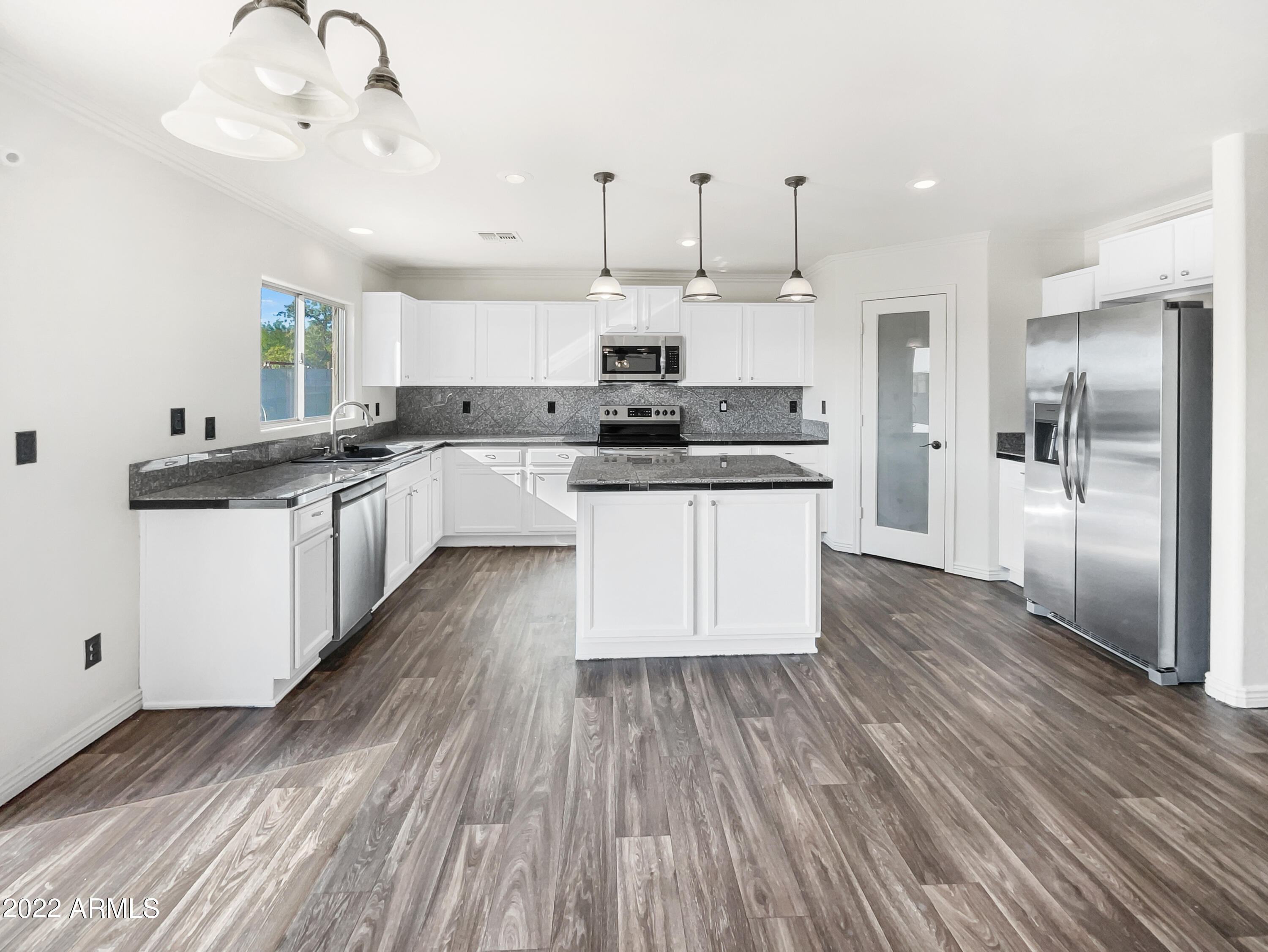 44011 West Cowpath Road Maricopa, AZ 85138 - Photo 7 of 18 a large kitchen with cabinets wooden floor and stainless steel appliances