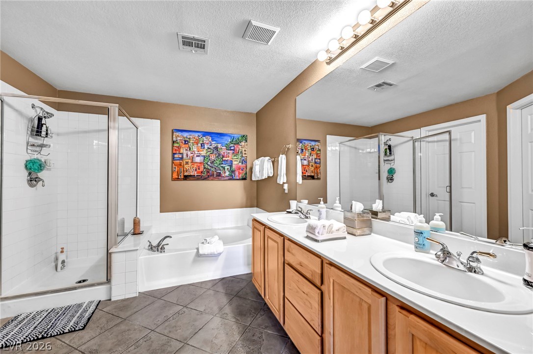 10730 Amber Ridge Drive, Unit 101 Las Vegas, NV 89144 - Photo 23 of 32 Indulge in a primary bathroom featuring dual sinks, a luxurious soaking tub, and a separate glass-enclosed shower.