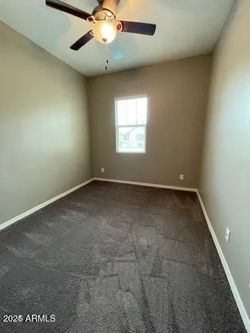 an empty room with a ceiling fan and window