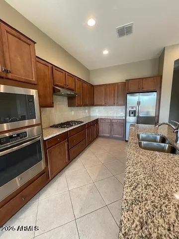 a kitchen with stainless steel appliances granite countertop a stove a sink and a microwave