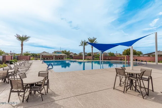 a view of a patio with dining table and chairs under an umbrella with palm trees
