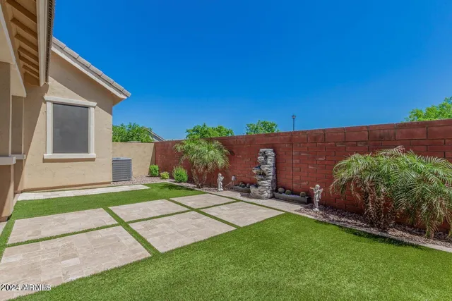 a backyard of a house with plants and large tree