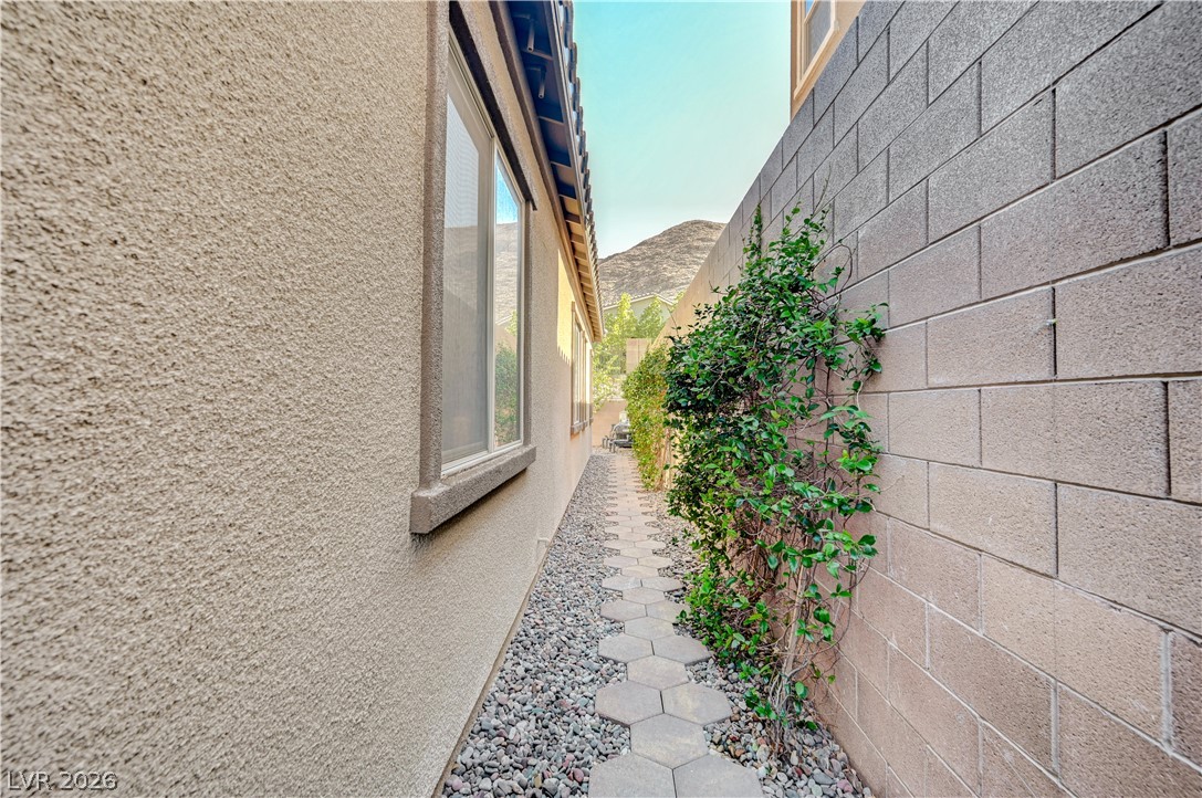 3943 Reyes Avenue Las Vegas, NV 89141 - Photo 62 of 95 A quaint pathway alongside the residence, adorned with hexagonal pavers and lush climbing greenery.