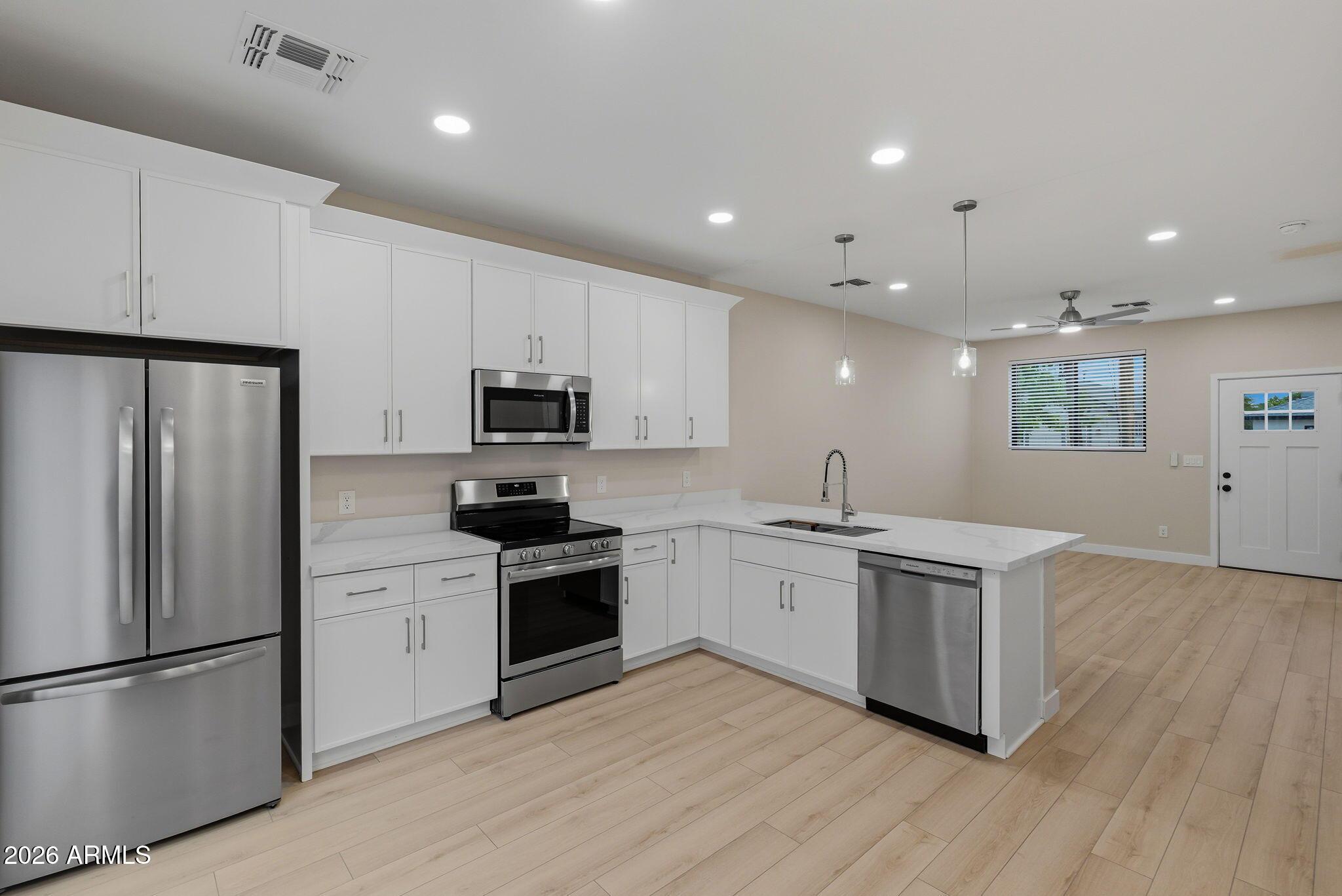 1222 East Diamond Street, Unit 2 Phoenix, AZ 85006 - Photo 15 of 35 a kitchen with stainless steel appliances granite countertop a stove a sink a refrigerator and white cabinets with wooden floor