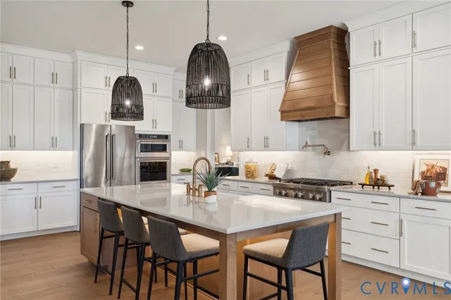 a kitchen with stainless steel appliances a sink a stove and chairs