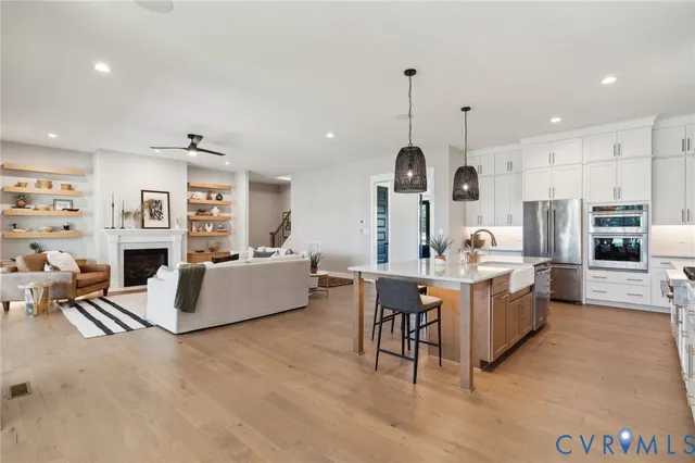 a large kitchen with kitchen island stainless steel appliances a table chairs sink and stove top oven