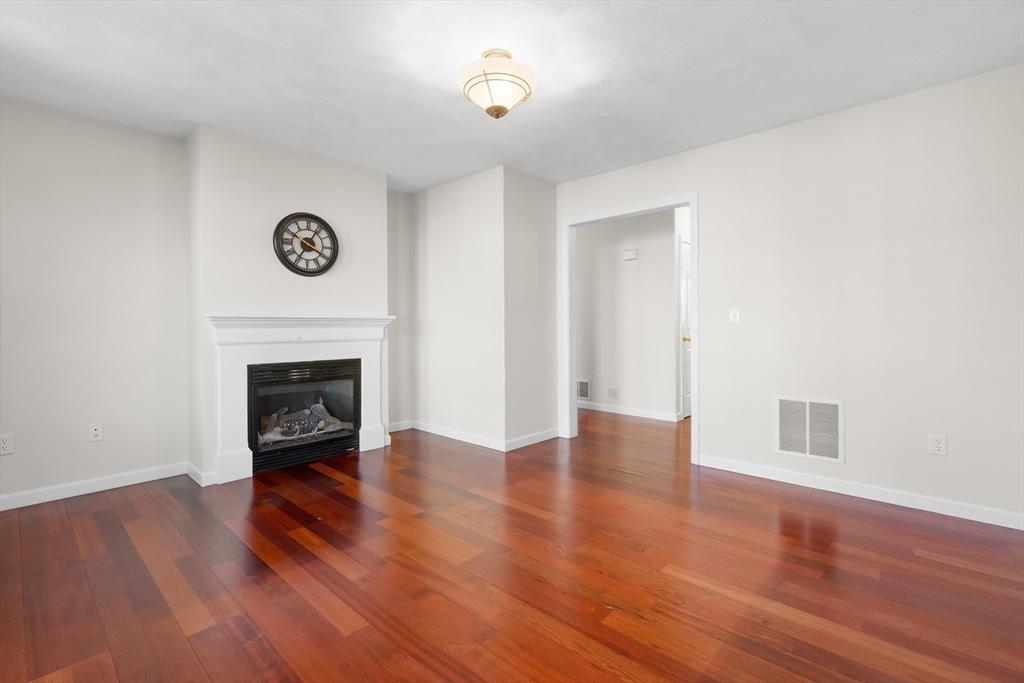 188 Beach Road, Unit 15 Salisbury, MA 01952 - Photo 10 of 39 an empty room with wooden floor and a fireplace