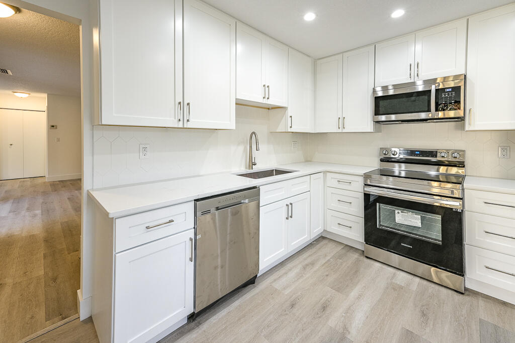 356 Prestwick Circle, Unit 3 Palm Beach Gardens, FL 33418 - Photo 18 of 42 a kitchen with stainless steel appliances granite countertop a stove a sink and a microwave