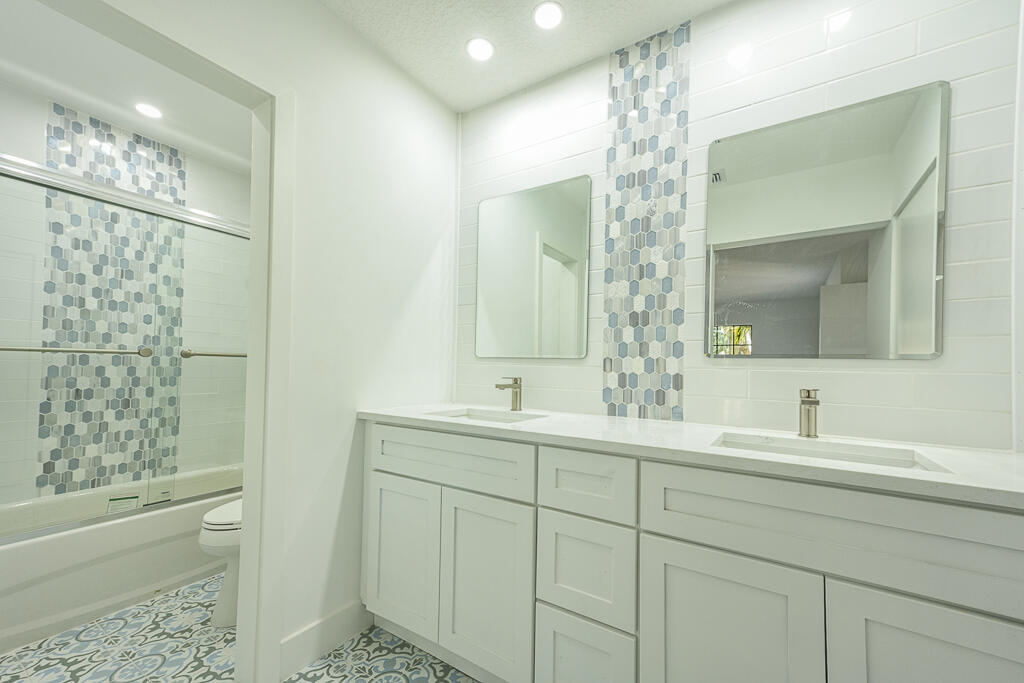 356 Prestwick Circle, Unit 3 Palm Beach Gardens, FL 33418 - Photo 26 of 42 a bathroom with double sink and a mirror