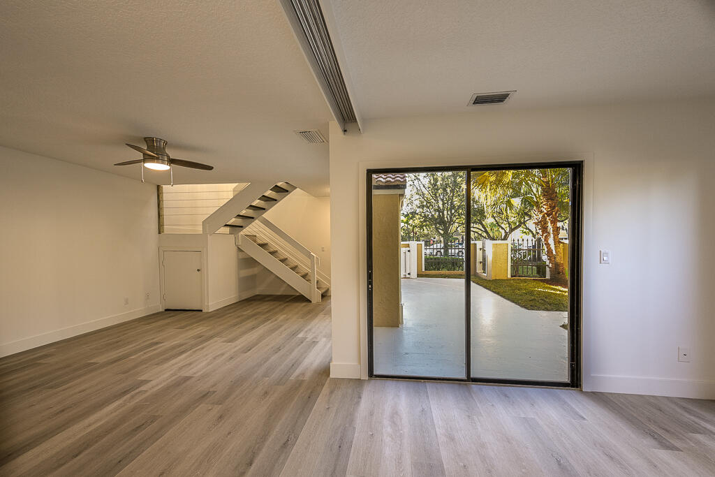 356 Prestwick Circle, Unit 3 Palm Beach Gardens, FL 33418 - Photo 10 of 42 an empty room with wooden floor staircase and windows