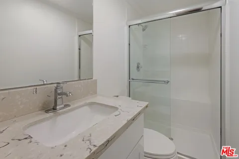 a bathroom with a granite countertop sink toilet and shower
