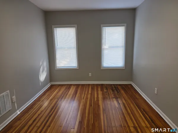 a view of an empty room with wooden floor and window