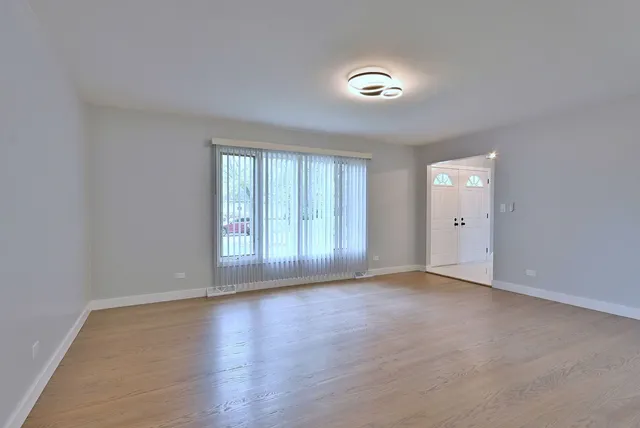 a view of an empty room with wooden floor and window