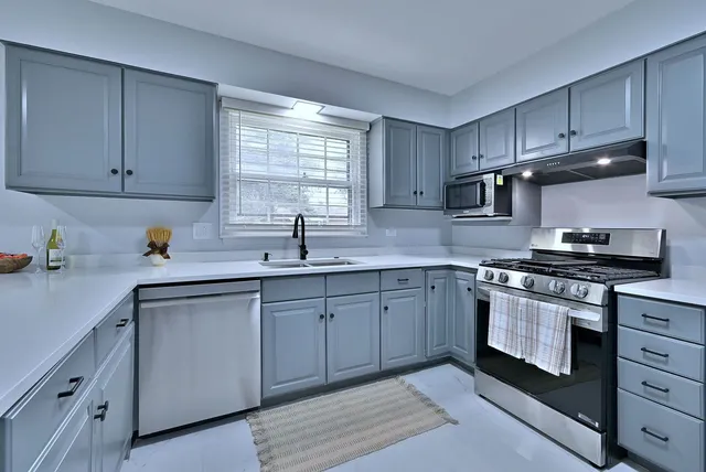a kitchen with cabinets appliances a sink and a window