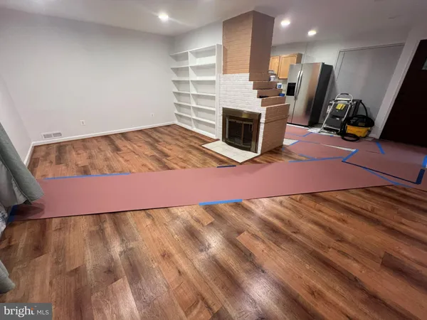 a view of kitchen and empty room with wooden floor