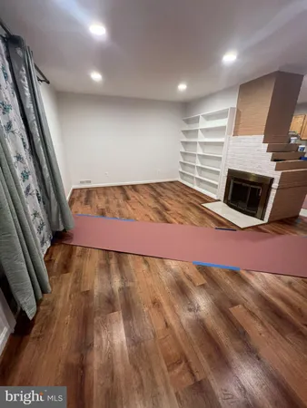 a view of an empty room with wooden floor and a fireplace