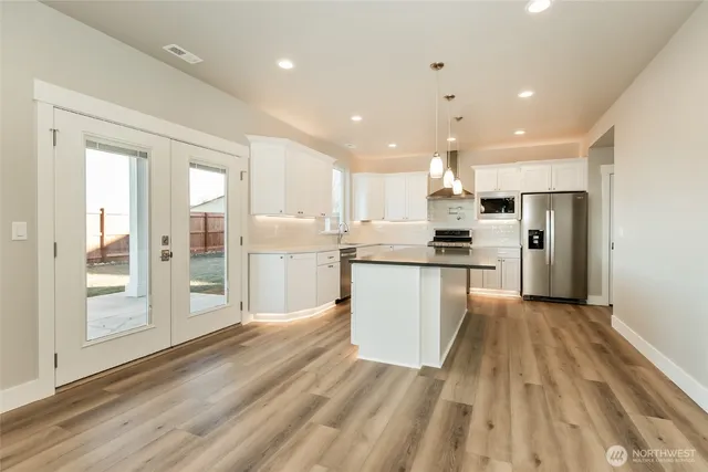 a large kitchen with kitchen island white cabinets and stainless steel appliances