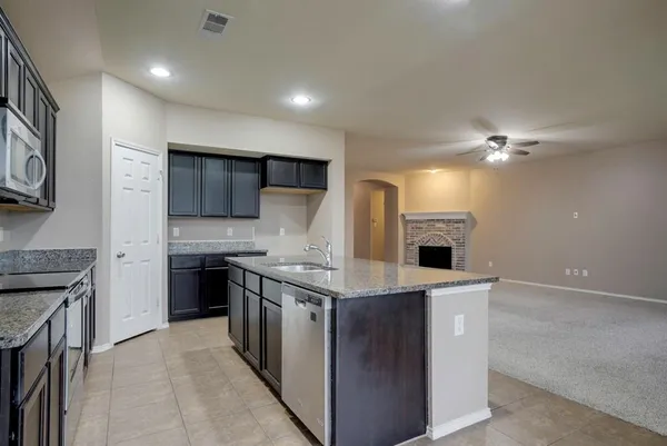 a large kitchen with stainless steel appliances granite countertop a stove a sink and a microwave