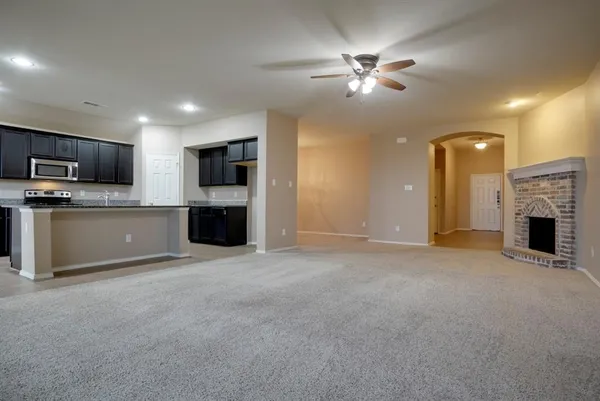 an empty room with a fireplace and a ceiling fan