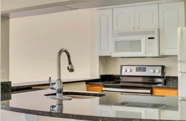 a kitchen with stainless steel appliances granite countertop a sink and a white cabinets