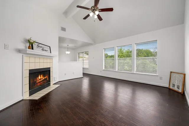 a view of an empty room with wooden floor fireplace and a window