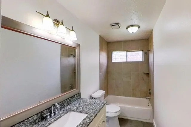a bathroom with a granite countertop sink a toilet and shower