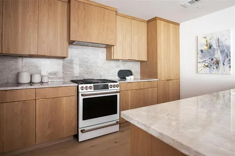 a kitchen with granite countertop a sink a stove and cabinets