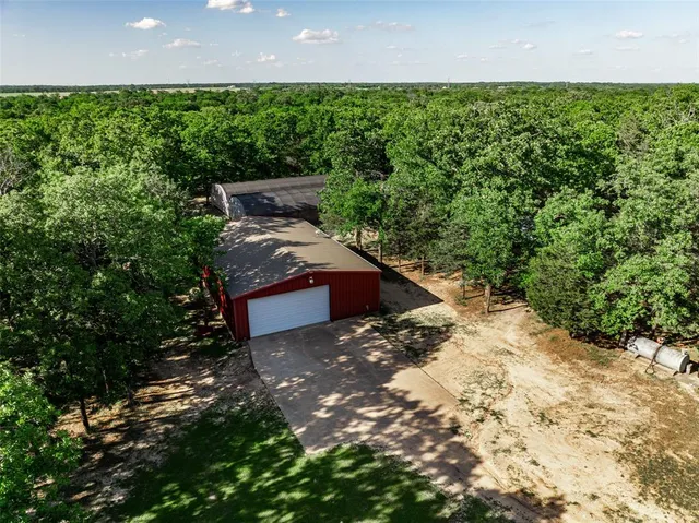 a view of a yard with plants and a bench under an umbrella